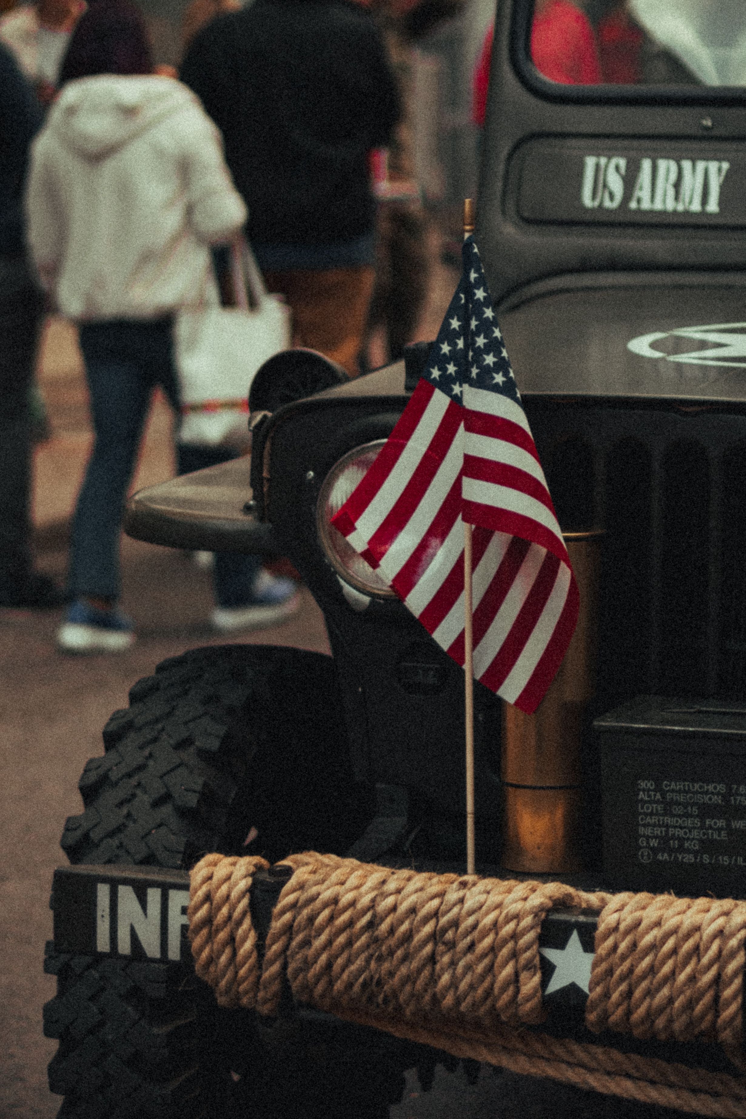 Vintage U.S. Army military jeep with an American flag displayed on the front during a patriotic event